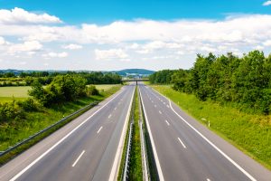 Empty highway through a green landscape with clouds on a blue sky